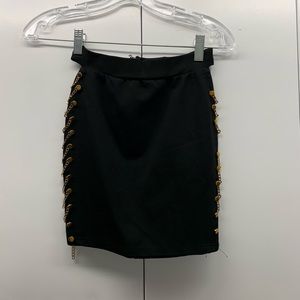 Fitted black skirt with gold chain on the side
